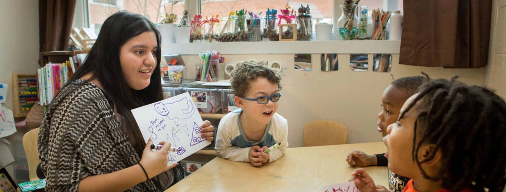 Teacher using visual aids to engage children in a Fast ForWord learning session.